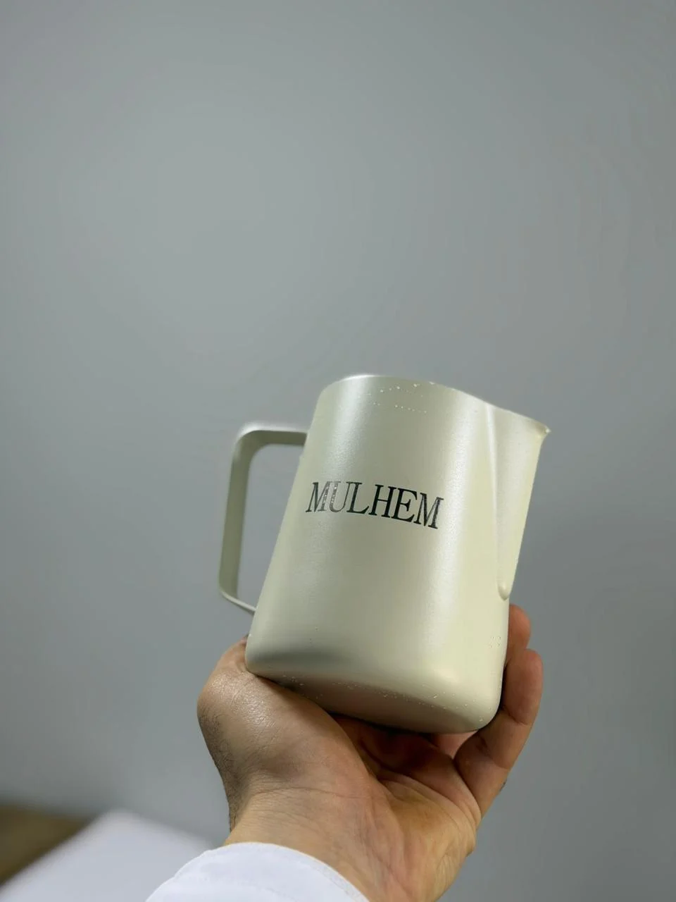 Laser-engraved milk pitcher with a café name