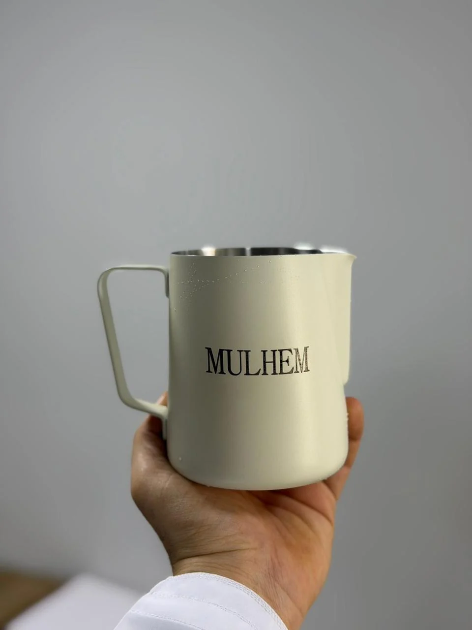 Laser-engraved milk pitcher held in hand
